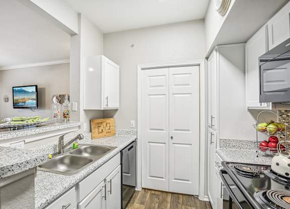 A kitchen with a sink, stove, and cabinets.