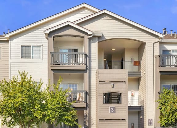 an apartment building with two balconies and a tree