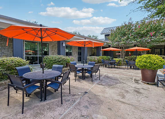A patio with tables and chairs under orange umbrellas.