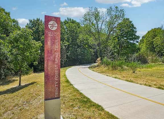 A sign for the Tancy Forest Shine Trail stands in front of a paved road.