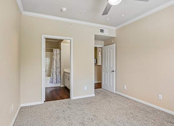 A room with a carpeted floor and a ceiling fan.