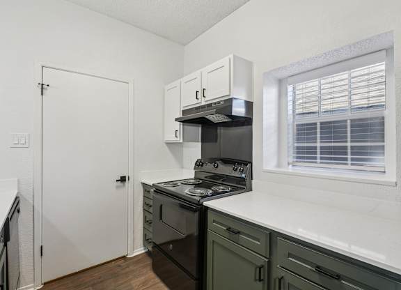 A kitchen with a stove, oven, and cabinets.