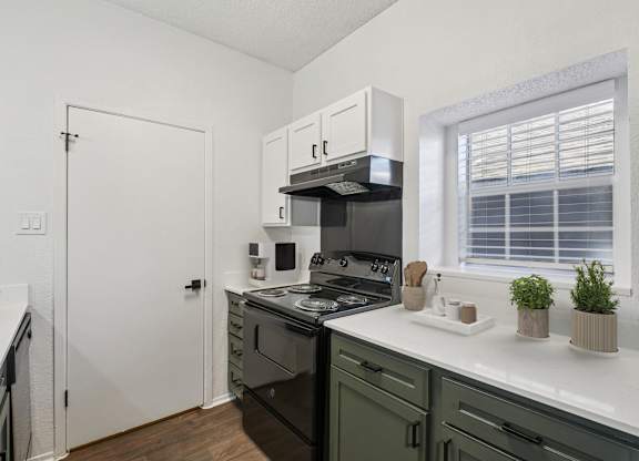 A kitchen with black appliances and white cabinets.