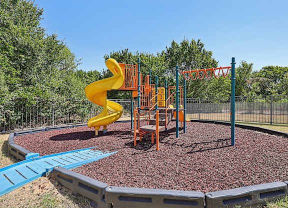 A playground with a yellow slide and orange climbing frame.