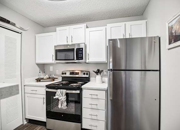 A kitchen with white cabinets and a stainless steel refrigerator.
