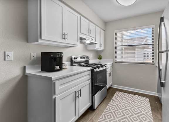 an open kitchen with white cabinets and a window and a refrigerator