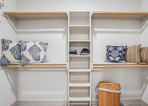 A white shelving unit with a blue and white pillow on it.