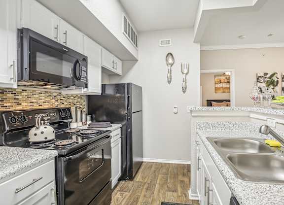 A kitchen with black appliances and white cabinets.