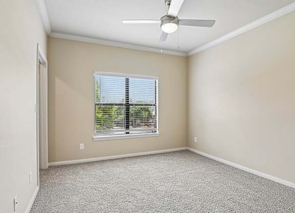 A room with a ceiling fan and a window with blinds.