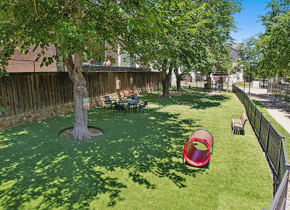 A backyard with a red slide and a green lawn.