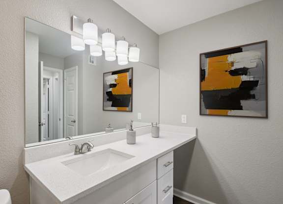 A bathroom with a white sink and a mirror.