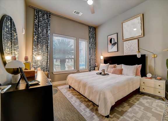A bedroom with a large bed, a dresser, and a mirror.