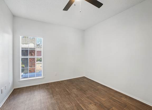 Empty room with a window and a ceiling fan.