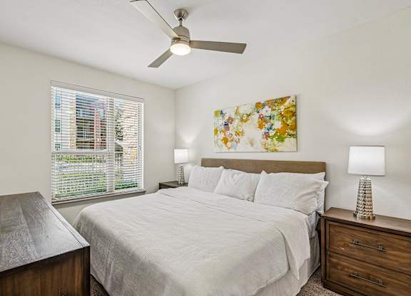 A bedroom with a bed, nightstand, and a painting on the wall.