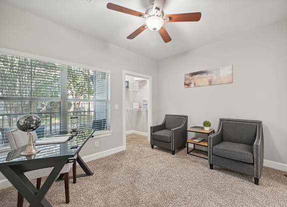 A room with a ceiling fan and three chairs.