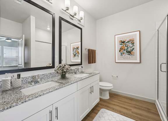 A bathroom with a toilet, sink, and a framed picture on the wall.