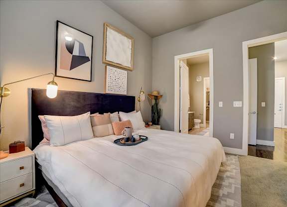 A bedroom with a large bed and a nightstand with a lamp.