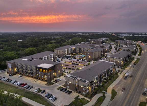 an aerial view of apartment buildings on a city street at sunset