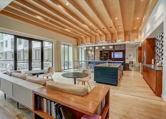 Spacious clubhouse with wood-slat ceiling, large island, and sliding doors to courtyard.