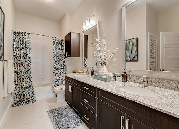 A bathroom with a sink, mirror, and shower curtain.