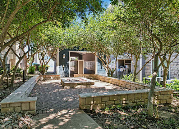 A courtyard surrounded by trees and a brick pathway.