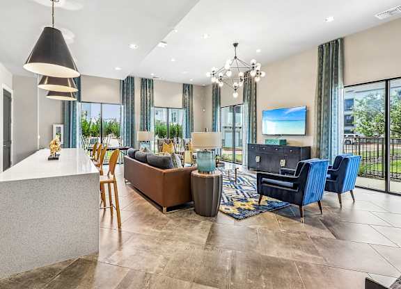 A modern living room with a large flat screen TV and a kitchen area.