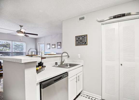 A kitchen with white cabinets and a black fridge.