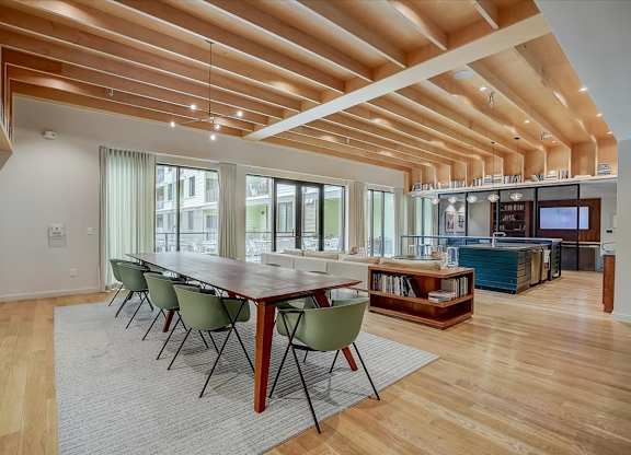Community dining table with modern chairs beneath dramatic wood ceiling beams.
