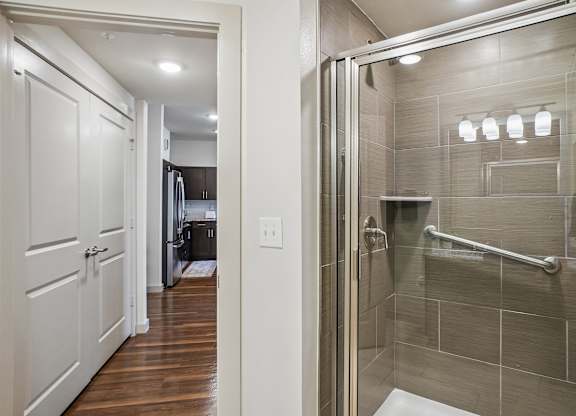 A white door is open to a bathroom with a walk-in shower.