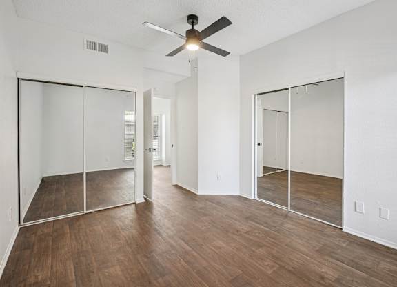 A room with a ceiling fan and sliding glass doors.