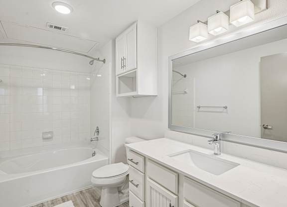 A white bathroom with a tub, toilet, and sink.