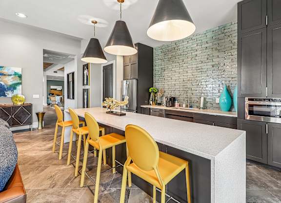 A kitchen with a white countertop and yellow chairs.