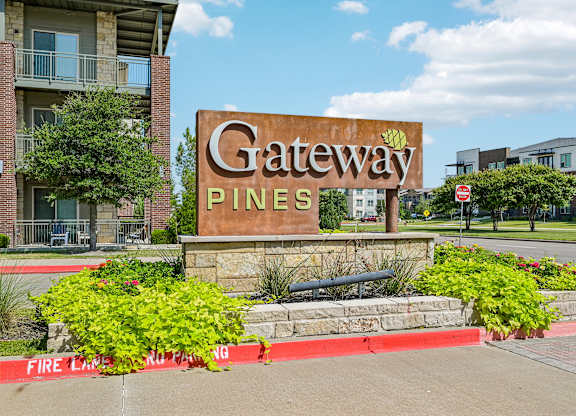 A sign that says "Gateway Pines" in front of a building.
