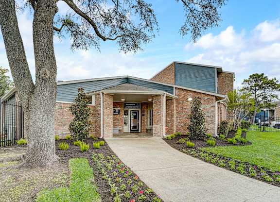 the front of a brick building with a tree and a sidewalk