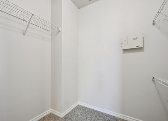 A white wall with a metal rack on the left side and a white electrical box on the right side.