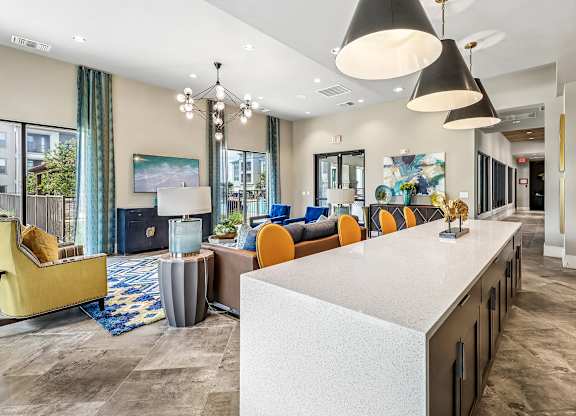 A modern living room with a white counter and orange chairs.