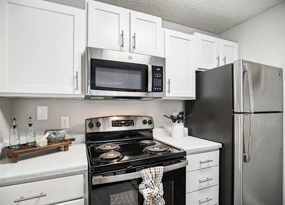 A modern kitchen with white cabinets and stainless steel appliances.