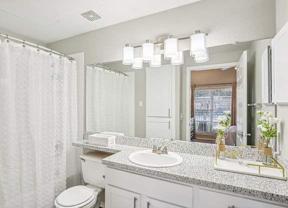 A bathroom with a white toilet, sink, and shower curtain.