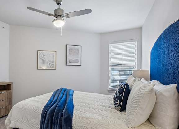 A bedroom with a bed covered in a blue blanket and two pillows.