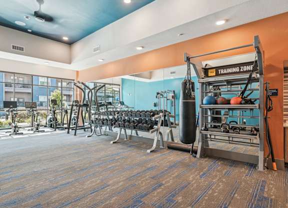 A gym with a variety of equipment including weights and a leg press machine.