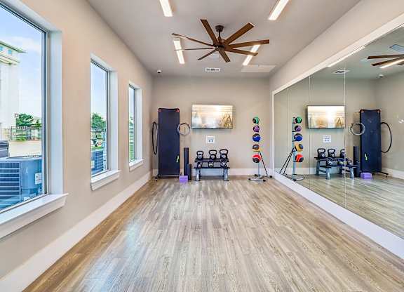 A gym with a mirror, weights, and exercise equipment.