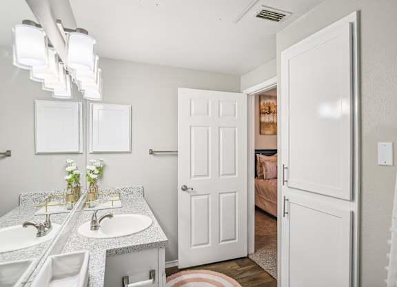 A bathroom with a double sink vanity and a white door.