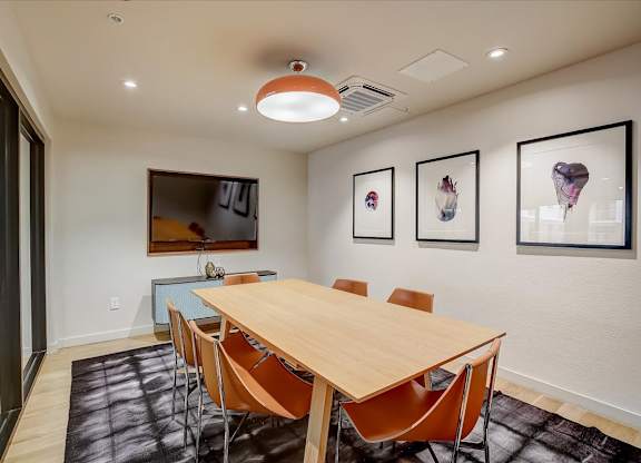Meeting space with wall-mounted TV, framed artwork, and conference table seating.