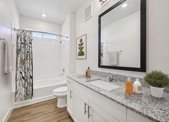 A bathroom with a white toilet, sink, and a mirror.