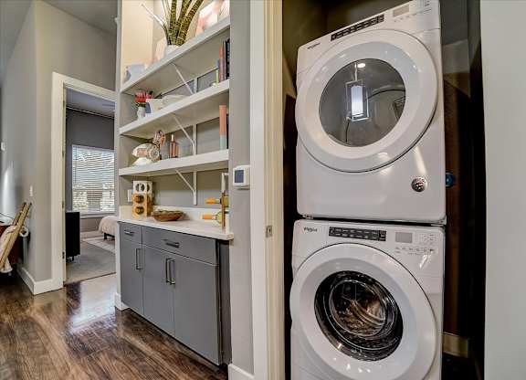 A white washing machine is stacked on top of a white dryer in a laundry room.