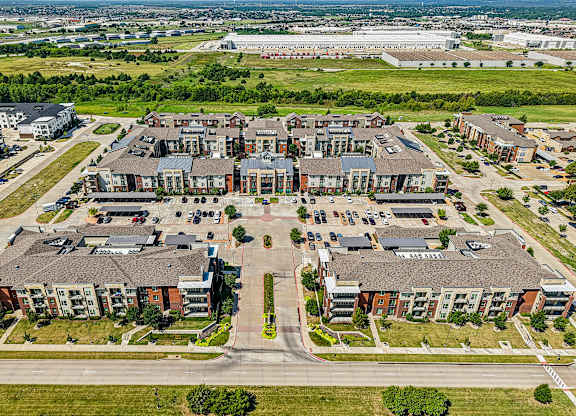 A large apartment complex with a parking lot in front.