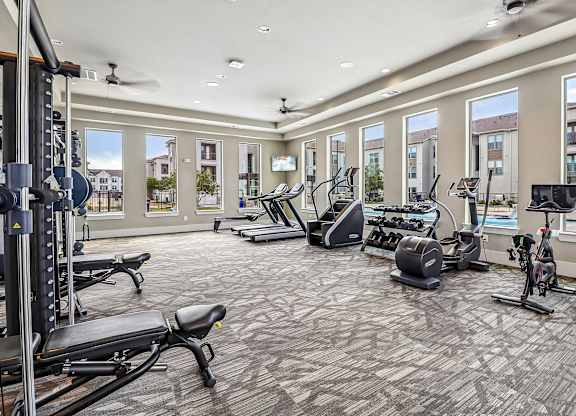 A spacious gym with a variety of equipment including treadmills, stationary bikes, and weight machines.