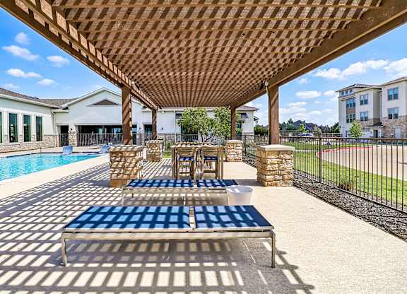 A wooden pergola over a blue and white checkered table.