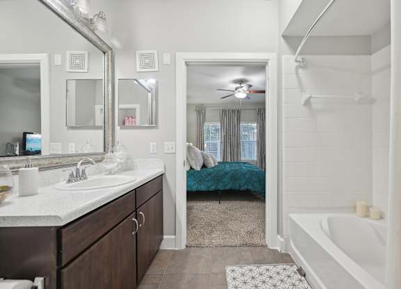 A bathroom with a white tub and a bed in the background.