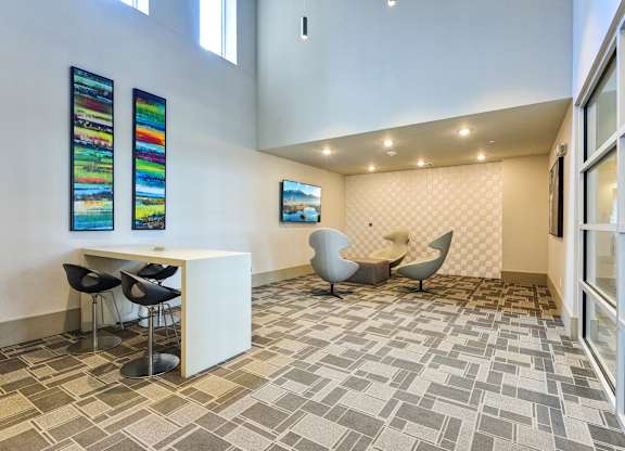 A room with a white desk and chairs, a painting on the wall, and a tiled floor.